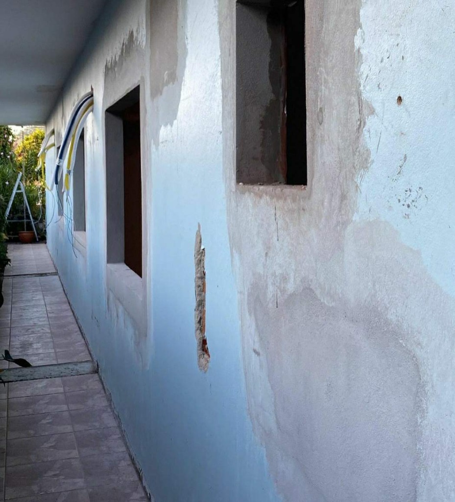 Antes da pintura externa: parede com reboco danificado e umidade